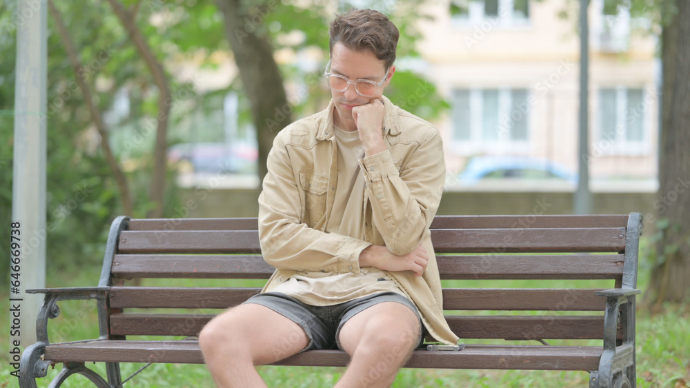 Fototapeta premium Tired Casual Young Man Sleeping while Sitting on Bench
