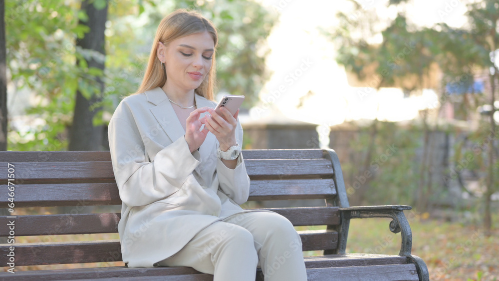 Young Business Lady using Phone while Sitting on Bench Young Business Lady using Phone while Sitting on Bench