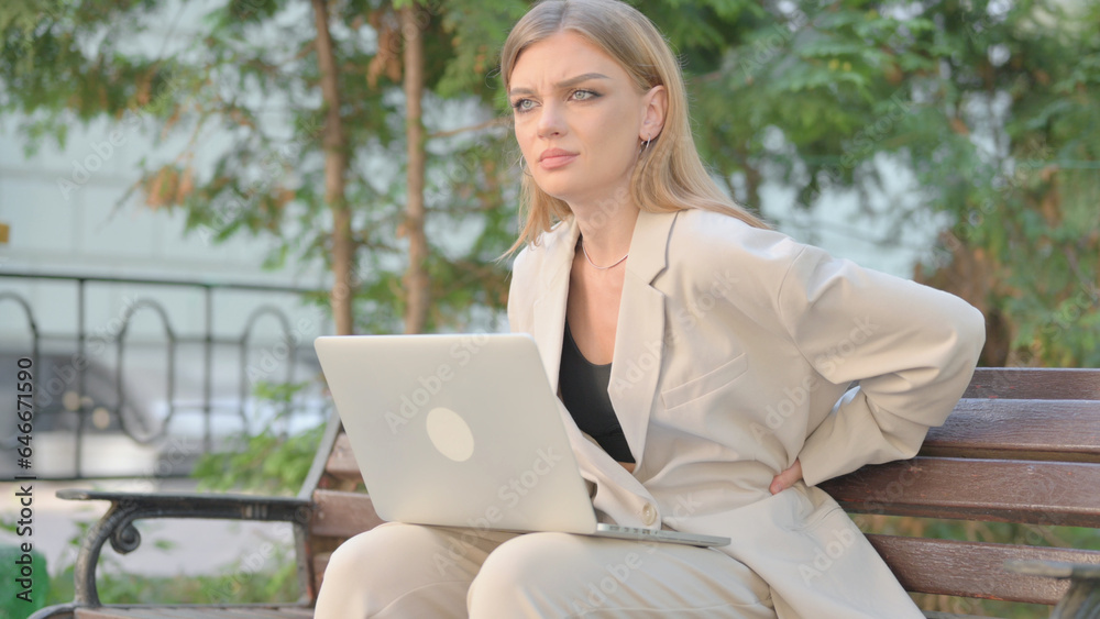 Young Business Lady Using Laptop with Back Pain while Sitting on Bench Young Business Lady Using Laptop with Back Pain while Sitting on Bench