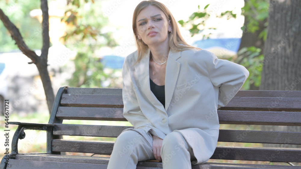 Young Businesswoman Sitting on Bench with Back Pain Young Businesswoman Sitting on Bench with Back Pain