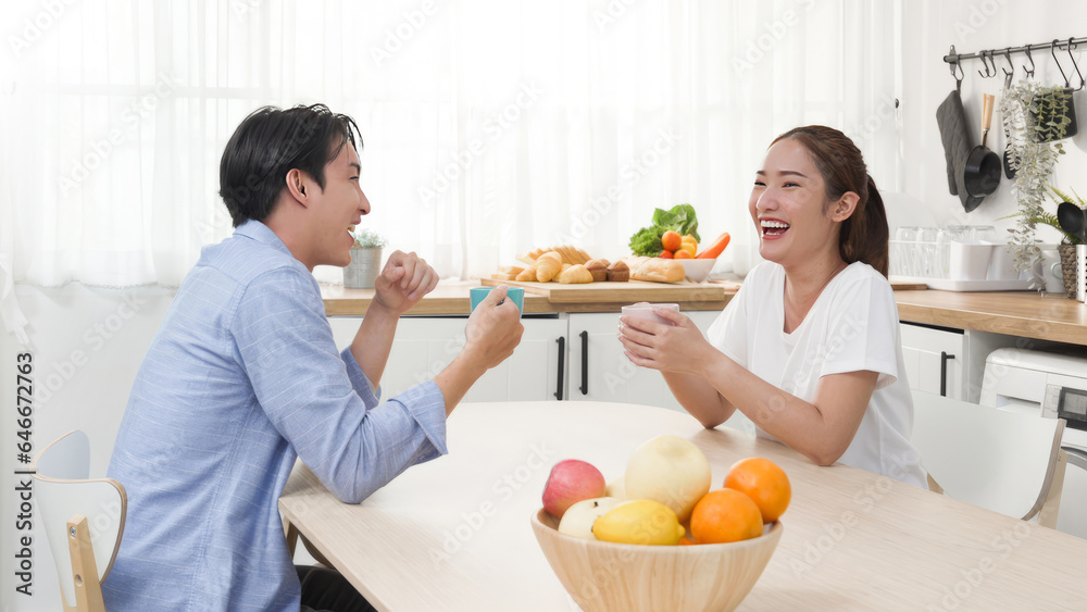 Asian couple teenager male and female cheerful smile and drink a cup of coffee breakfast with morning talk together in the kitchen studio at cozy home Asian couple teenager male and female cheerful smile and drink a cup of coffee breakfast with morning talk together in the kitchen studio at cozy home