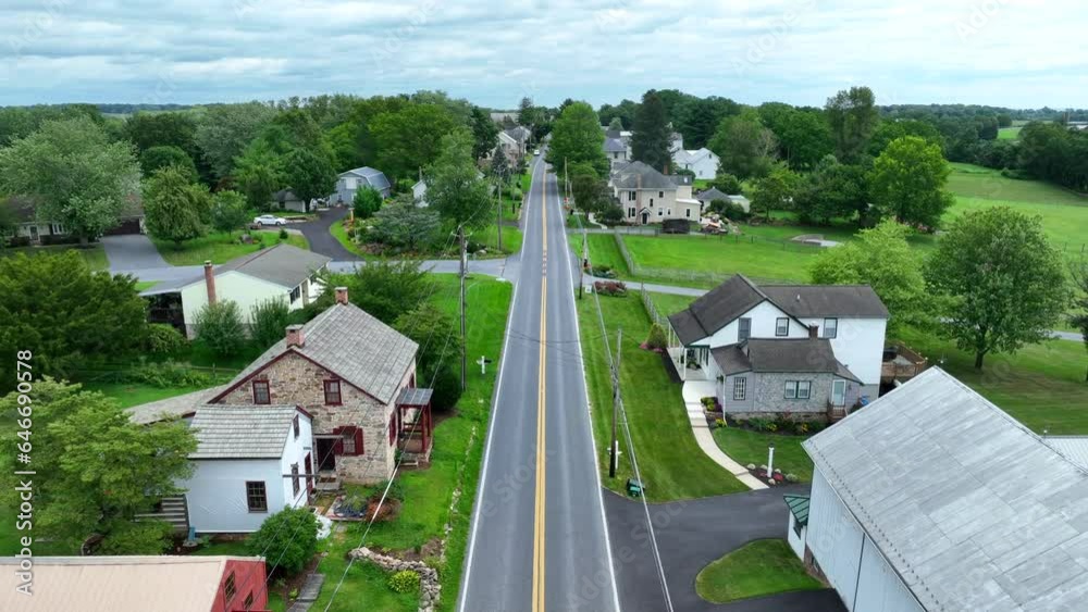 Historic street with houses in small rural town in USA. Aerial shot above road on summer day with green grass and trees. Historic street with houses in small rural town in USA. Aerial shot above road on summer day with green grass and trees.