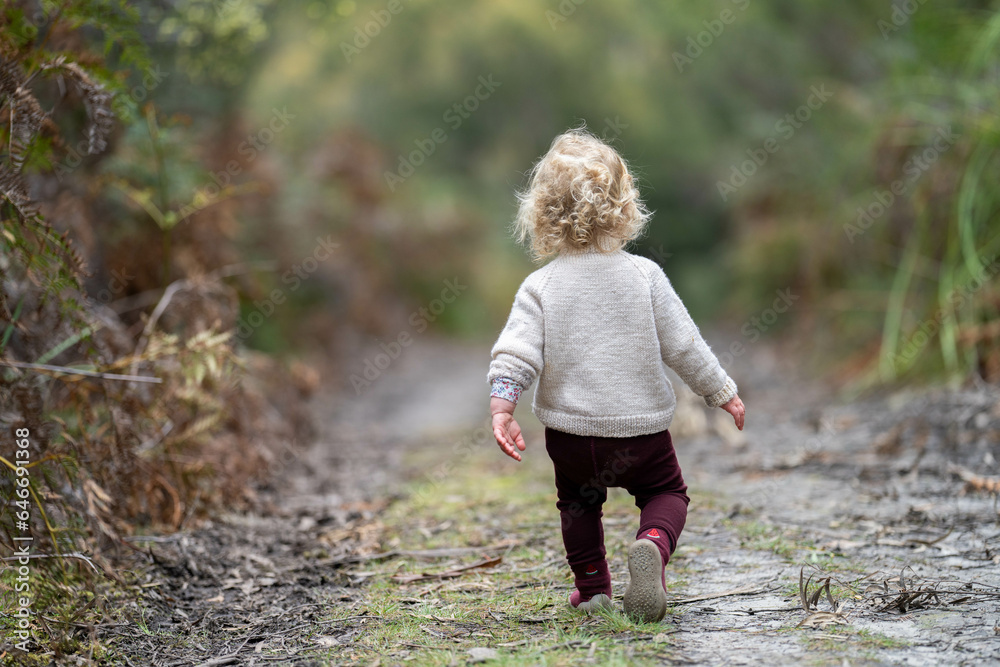 blonde todder walking in a forest on a hike in spring blonde todder walking in a forest on a hike in spring