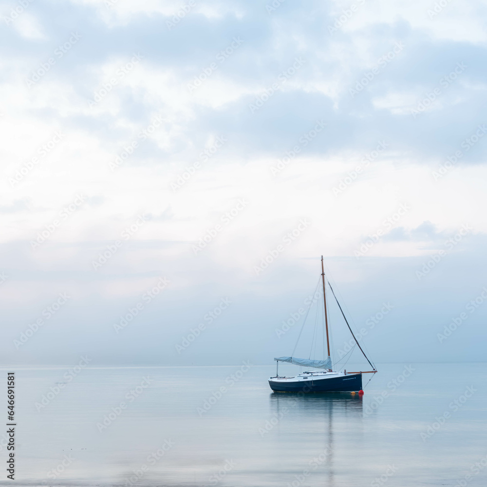 a yacht anchored near the shore at morning blue hour prior to sunrise. a yacht anchored near the shore at morning blue hour prior to sunrise.