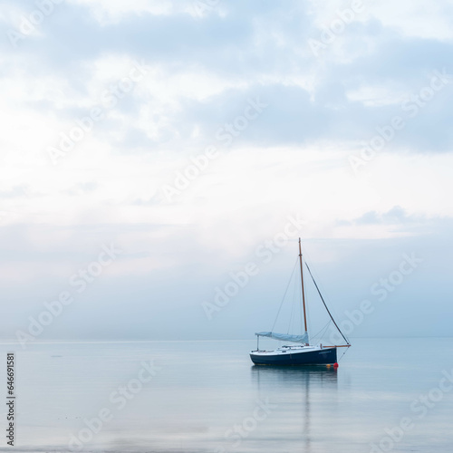 a yacht anchored near the shore at morning blue hour prior to sunrise.
