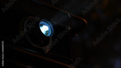 Video projector for an outdoor cinema. 4K detail video with the lens and light trail from a cinema movie projector in the evening.