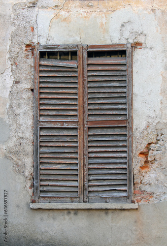 old window with shutters  an ancient wall facade with slightly broken wooden window perfect as background textures