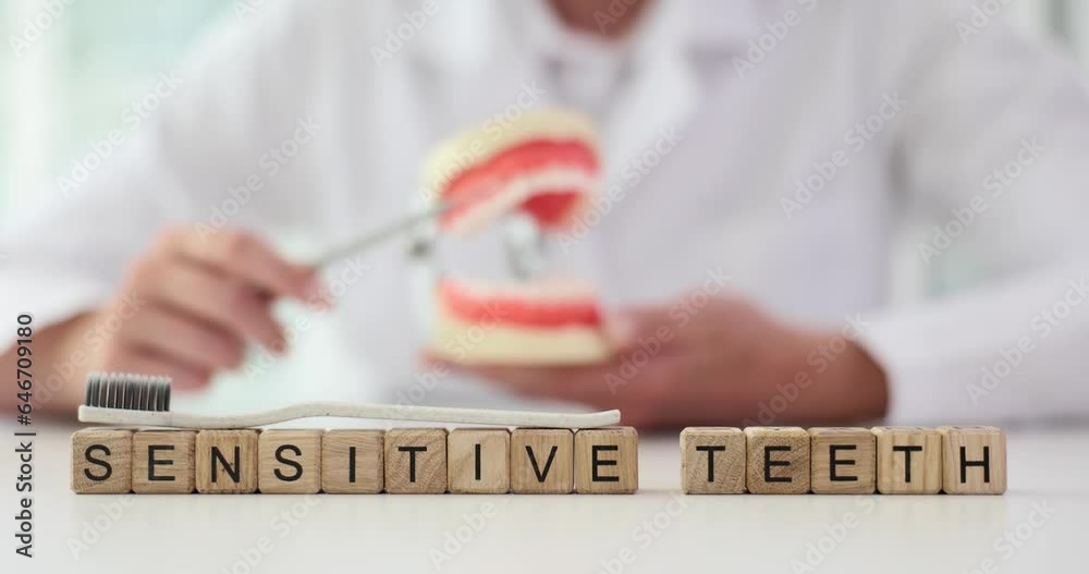 Dentist cleans teeth of artificial jaw model word sensitive teeth. Increased sensitivity of hard dental tissues