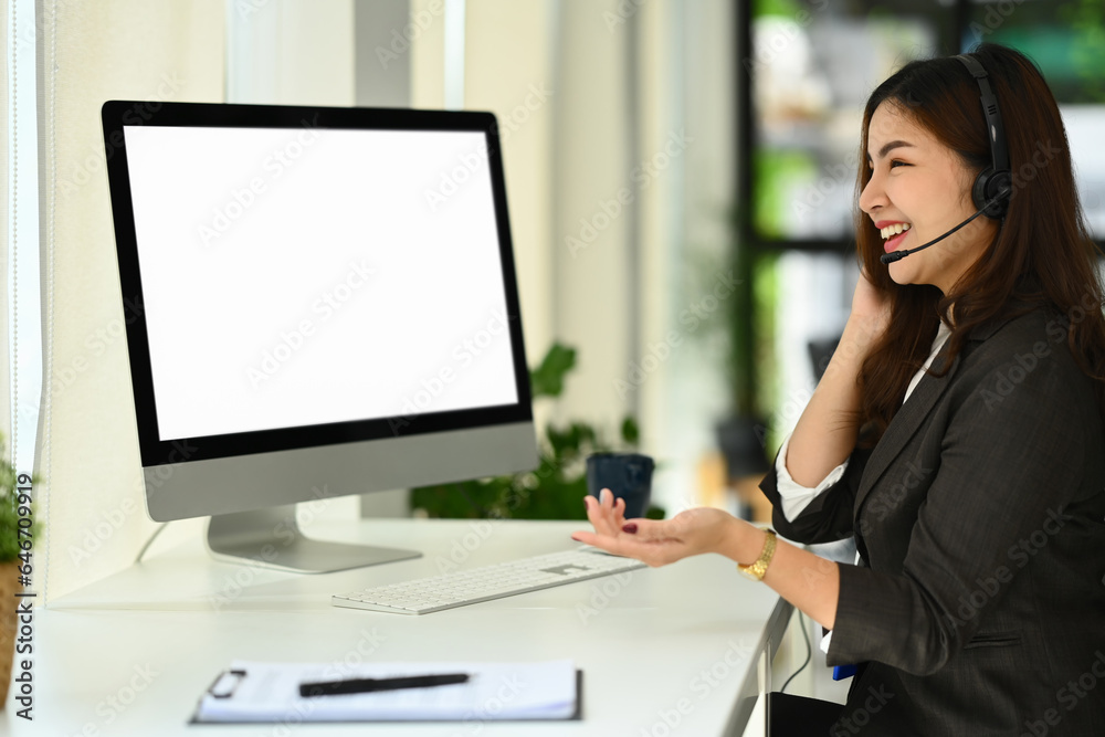 Side view of friendly telemarketer or telesales agent using headset consulting online with client on computer Side view of friendly telemarketer or telesales agent using headset consulting online with client on computer