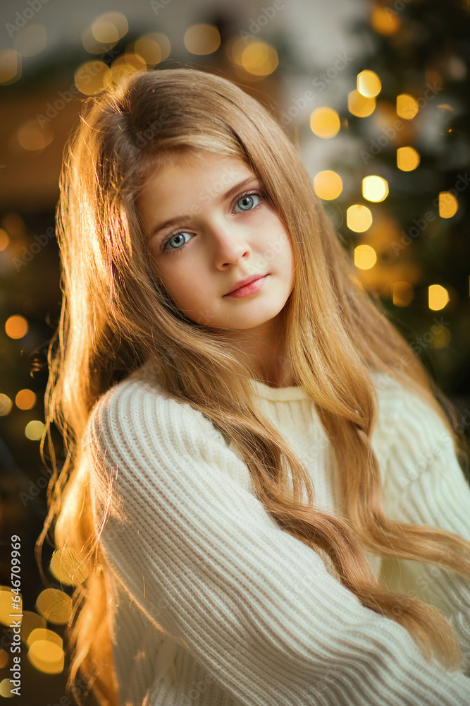 Close up portrait  of beautiful young girl with long curly blonde hair on a christmas background with boke lights. Magic warm new year photo.Cozy interior.