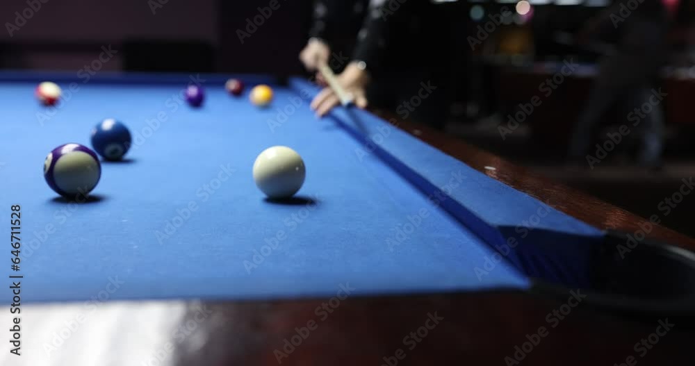 Billiard player hits ball on blue billiard table in club. Player loves to play billiards