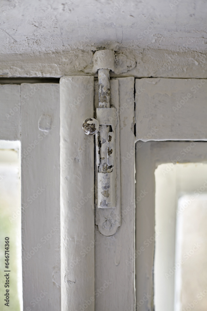 A dilapidated old window frame with a metal window latch. Renovation in an old house A dilapidated old window frame with a metal window latch. Renovation in an old house