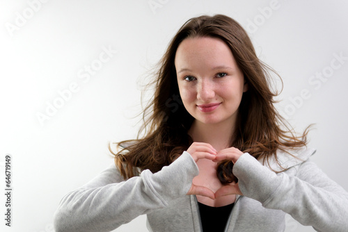 Close up of happy young woman smiling and showing hands sign heart shape looking at camera. Healthy heart health life insurance, love and charity, voluntary social