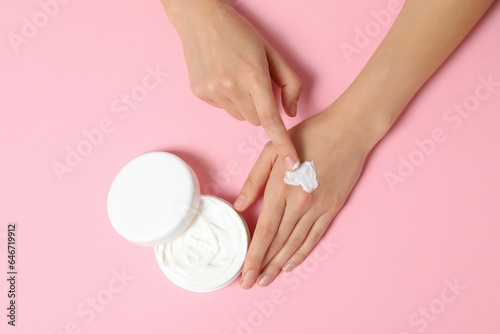 A jar of hand cream on a light pink background.