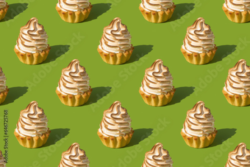 Seamless pattern of holiday cakes with flamed white meringue on a green background