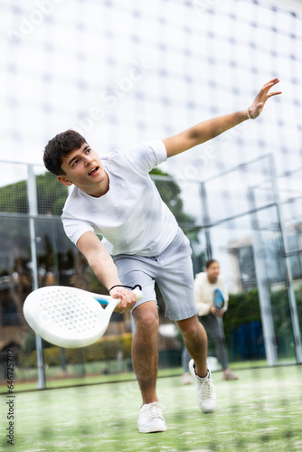 View through the tennis net of an young playing padel © JackF