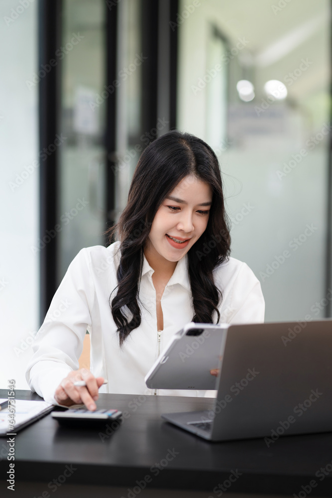 Businesswoman working with tablet and using a calculator to calculate the numbers of static in office. Finance accounting concept. Businesswoman working with tablet and using a calculator to calculate the numbers of static in office. Finance accounting concept.