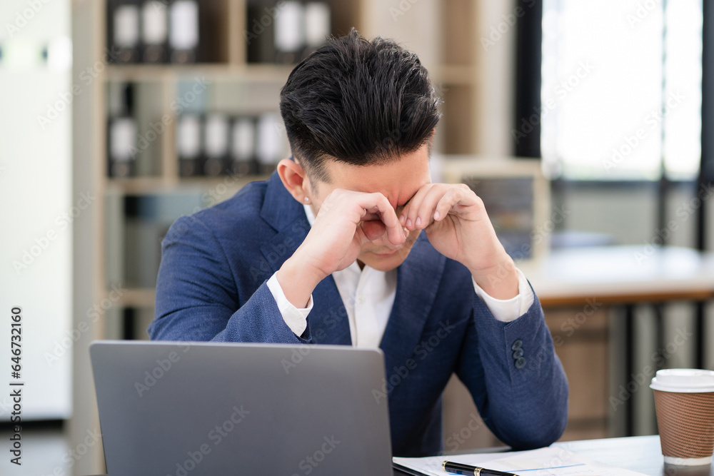 tired male businessman works at office on a laptop, works from office. tired male businessman works at office on a laptop, works from office.