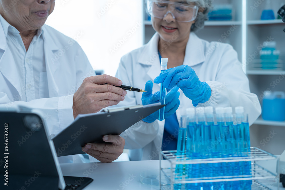 Fototapeta premium Medical Research Laboratory: Two scientists working, using digital tablets, analyzing samples, talking, developing biotechnology.