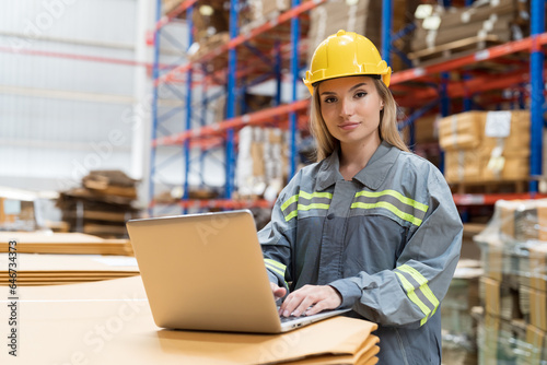 Female warehouse worker working with laptop computer for check stock in warehouse. Woman warehouse worker inspecting quality of barcodes on boxes on shelves pallet in storage warehouse