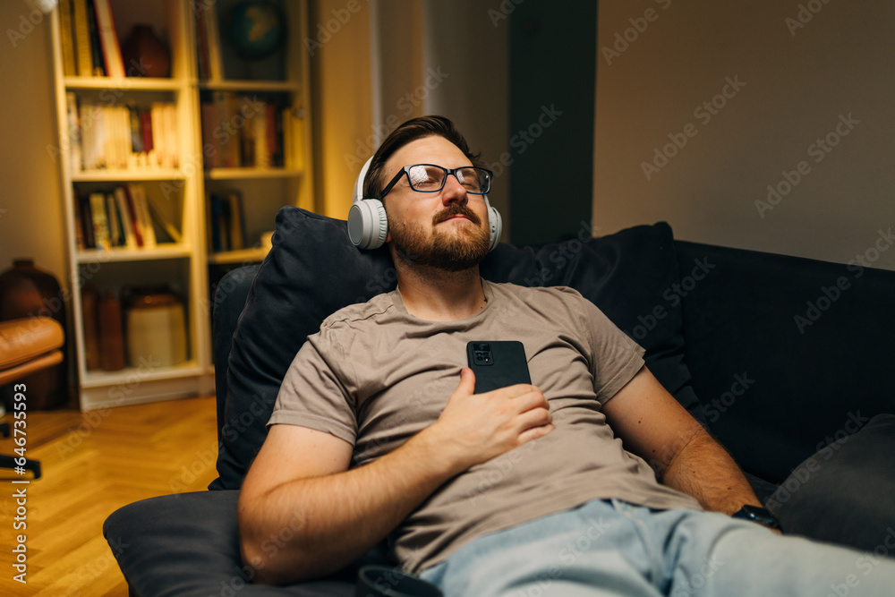 Man with headphones listening to music at home in the evening.