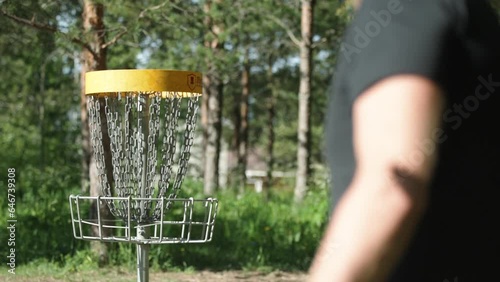 Person throwing a frisbee to a frisbeegolf basket in slow motion photo