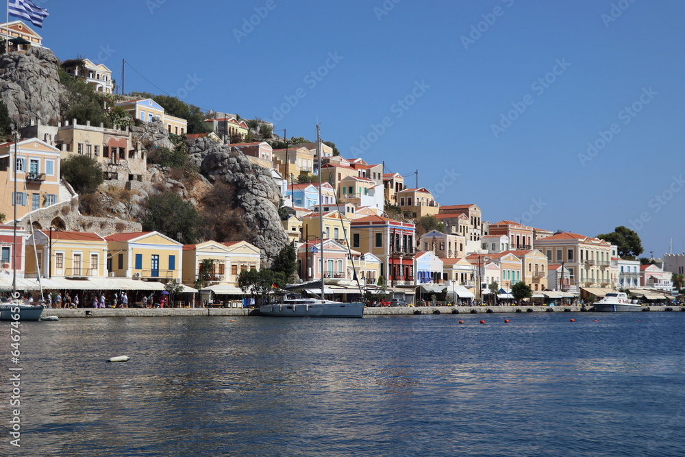 Symi Island, Greece. Greece islands holidays from Rhodos in Aegean Sea. Colorful neoclassical houses in bay of Symi. Holiday travel background