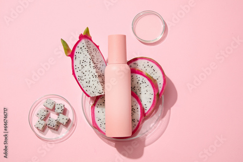 Few slices of white dragon fruit placed on a glass petri dish with an empty label bottle. Container packaging of skin care branding design of Dragon fruit (Hylocereus) extract