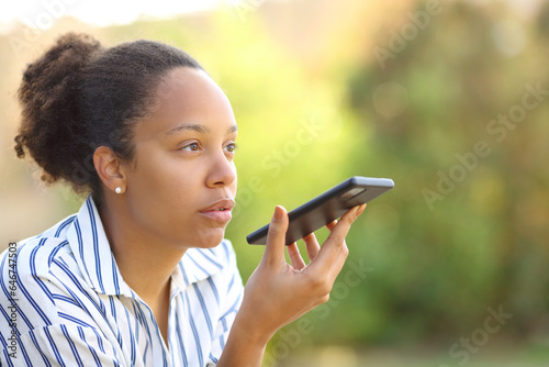 Photos Black woman dictating text on phone in a garden