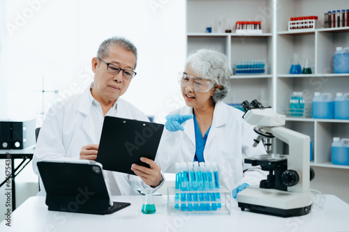 Two scientist or medical technician working, having a medical discuss meeting with Asian senior female scientist supervisor in the laboratory with online reading, test samples and innovation