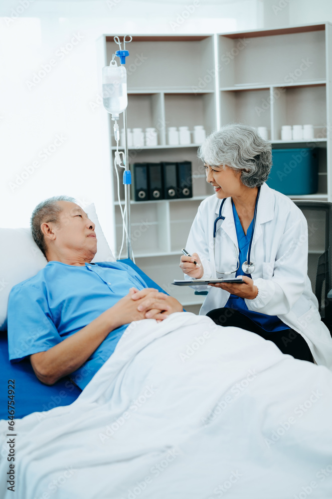Friendly Female Head Nurse Making Rounds does Checkup on Patient Resting in Bed. She Checks tablet while Man Fully Recovering after Successful Surgery in hospital Friendly Female Head Nurse Making Rounds does Checkup on Patient Resting in Bed. She Checks tablet while Man Fully Recovering after Successful Surgery in hospital