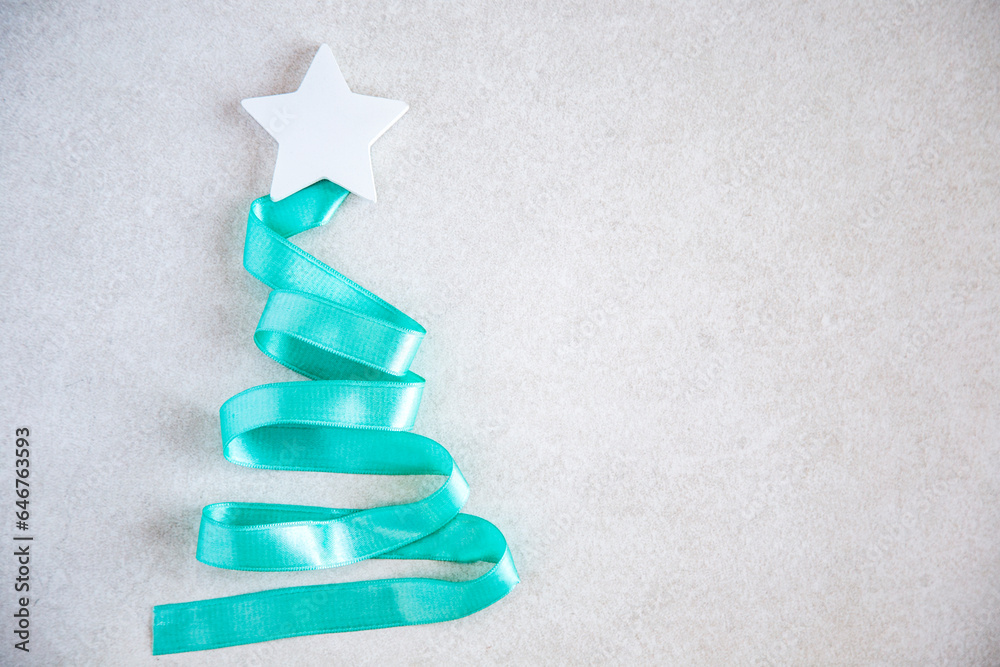 christmas tree made from blue turquoise ribbon with white star on grey stone background. Abstract photo with copy space. New Year or Christmas celebration concept christmas tree made from blue turquoise ribbon with white star on grey stone background. Abstract photo with copy space. New Year or Christmas celebration concept