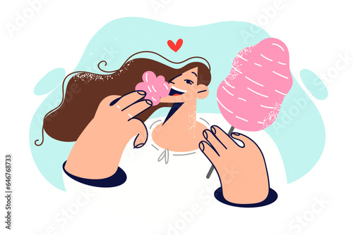 Carefree woman eats cotton candy, walking in park and enjoying sweet taste of street dessert