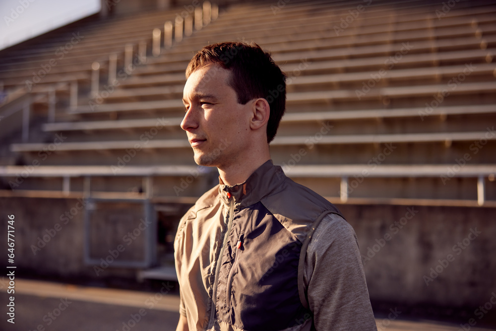 Confident young man standing on an outdoor running track