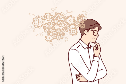 Thoughtful business man thinks about ways to automation production and improve work productivity. Guy engineer in white shirt scratches chin and thinks about possibilities of factory automation.