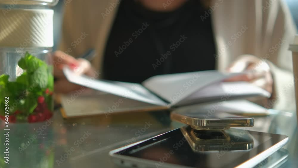 Young business woman sitting at table and writing in notebook. On table is smartphone, and tablet. Freelancer working, writing down new ideas 4K Young business woman sitting at table and writing in notebook. On table is smartphone, and tablet. Freelancer working, writing down new ideas 4K