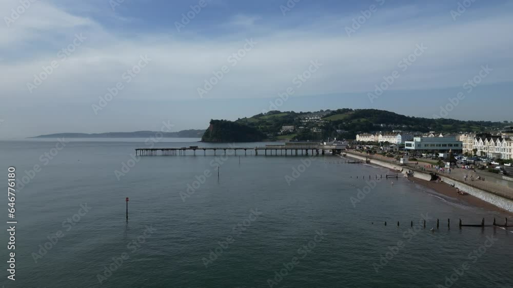 Teignmouth, South Devon, England: DRONE VIEWS: The drone flies at high speed directly toward Teignmouth Pier with the Ness sandstone escarpment in the b/g. Teignmouth is a popular UK holiday resort. Teignmouth, South Devon, England: DRONE VIEWS: The drone flies at high speed directly toward Teignmouth Pier with the Ness sandstone escarpment in the b/g. Teignmouth is a popular UK holiday resort.