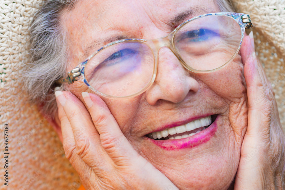 Close up of old senior woman smiling and holding her face with hands. Happiness and youthness concept lifestyle with old female people enjoying life. Mature lady smile and wear glasses. Perfect teeth Close up of old senior woman smiling and holding her face with hands. Happiness and youthness concept lifestyle with old female people enjoying life. Mature lady smile and wear glasses. Perfect teeth