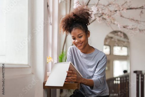 Beautiful african american young woman sit by the window and read a book