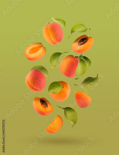 Fresh orange apricot, pink side, green leaves as flow fly, fall as art composition. Whole, half, piece fruits on satureted warm green background. Summer fruits for advertising, design, label product. photo