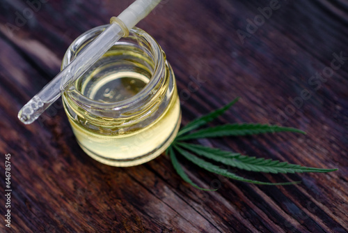 drop of hemp oil and cannabis leaves placed on dark background, medical concepts, alternative medicine, cbd oil, the pharmaceutical and therapeutic industries.