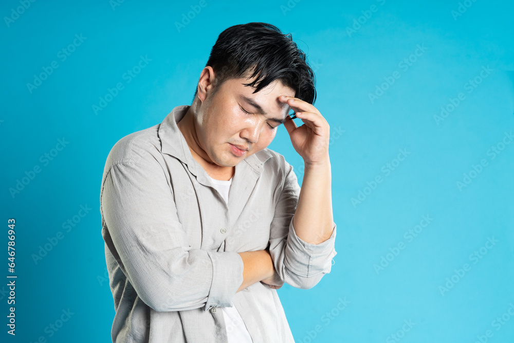 Image of Asian man having health problems, isolated on blue background Image of Asian man having health problems, isolated on blue background
