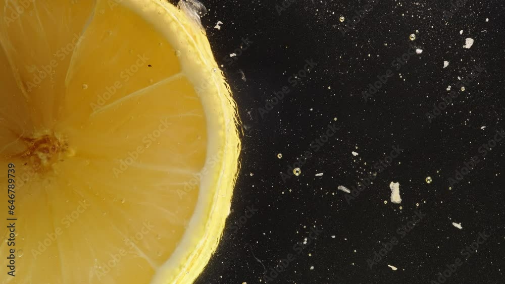 A lemon slice on a glass plate, viewed from below, with juice dripping and dissolving honey around it. Macro shot.