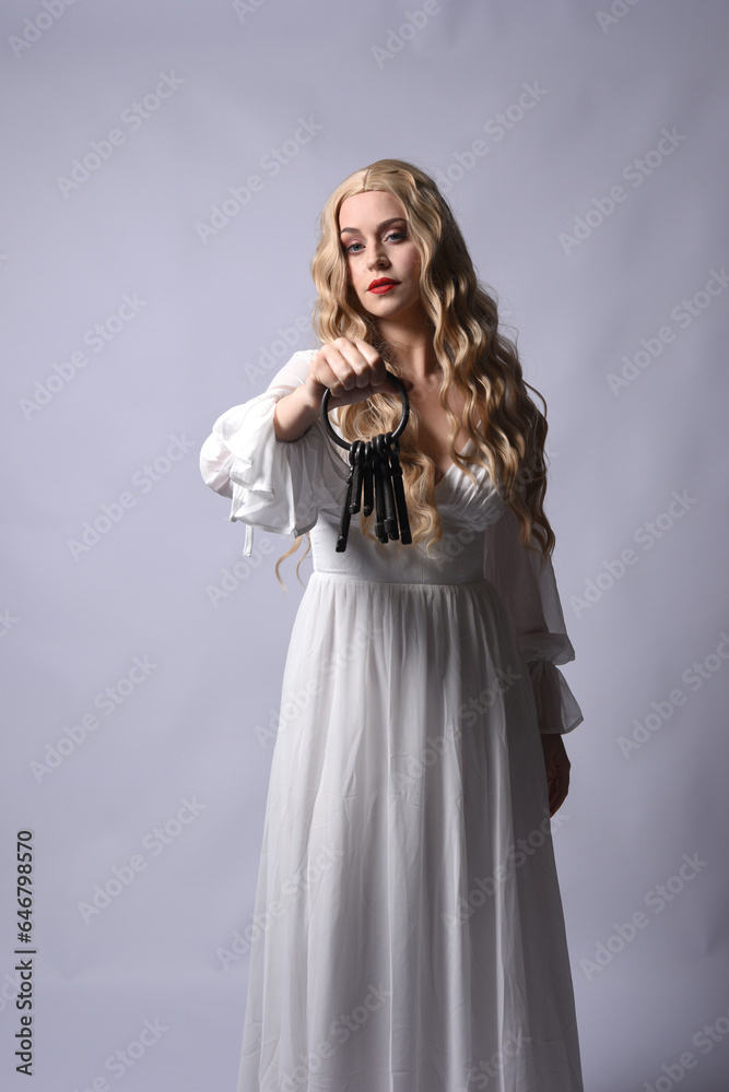 Close up portrait of beautiful blonde model wearing elegant white halloween gown, a historical fantasy character. Holding old key chain, isolated on studio background. Close up portrait of beautiful blonde model wearing elegant white halloween gown, a historical fantasy character. Holding old key chain, isolated on studio background.