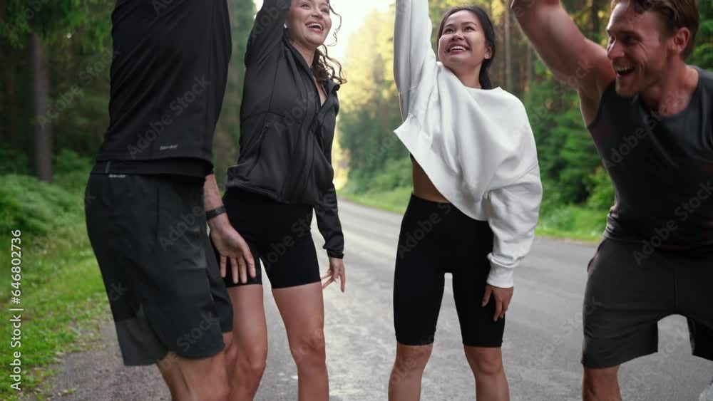 Positive athlete multiethnic friends show gesture of one for all and all for one before running down the road on morning in the woods