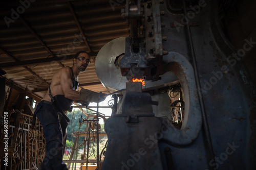 Fototapeta Naklejka Na Ścianę i Meble -  Blacksmith working a piece of steel on a mechanical hammer.