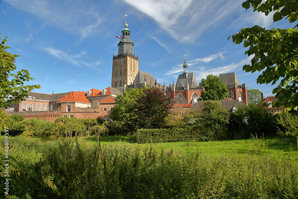 Saint Walburgiskerk church and historic medieval houses surrounded by fortifications in Zutphen, Gelderland, Netherlands, with green gardens in the foreground