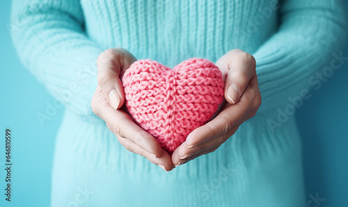 Frau hält pinkfarbenes gestricktes Herz in beiden Händen