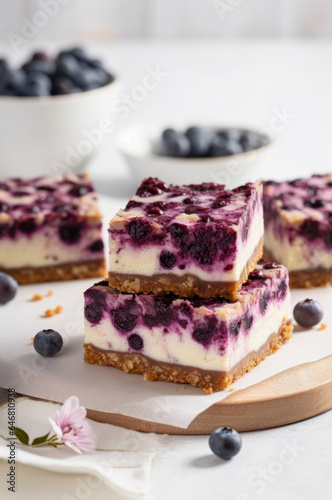 Stack of Blueberry Cheesecake Bars on light kitchen table with fresh blueberry on background. Vertical  side view.