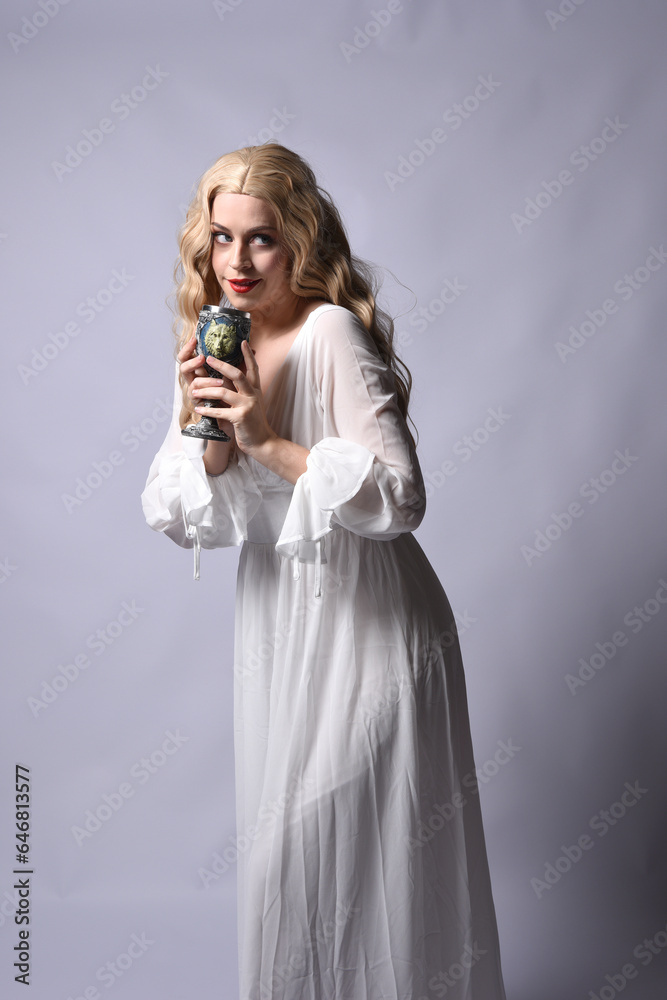 Close up portrait of beautiful blonde model wearing elegant white halloween gown, a historical fantasy character. Holding wine goblet, isolated on audio background. Close up portrait of beautiful blonde model wearing elegant white halloween gown, a historical fantasy character. Holding wine goblet, isolated on audio background.